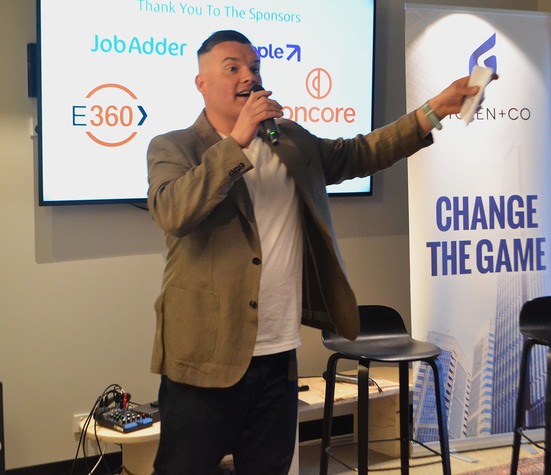 Steve speaking at a Change the Game event with sponsor logos
